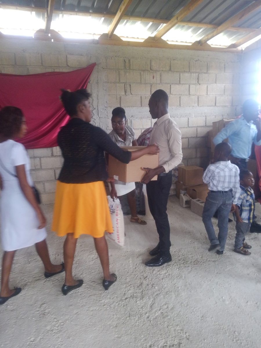 People carrying boxes at a Bread of Hope food distribution in Laferoney