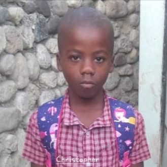 Christopher, a young student wearing a backpack, standing in front of a stone wall
