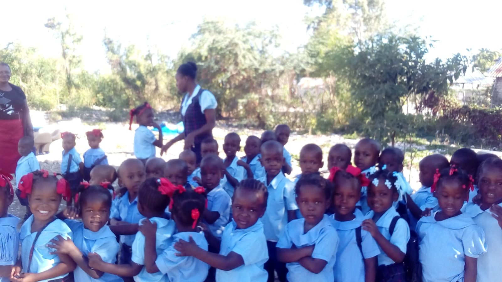 A large group of students in blue uniforms outside the school