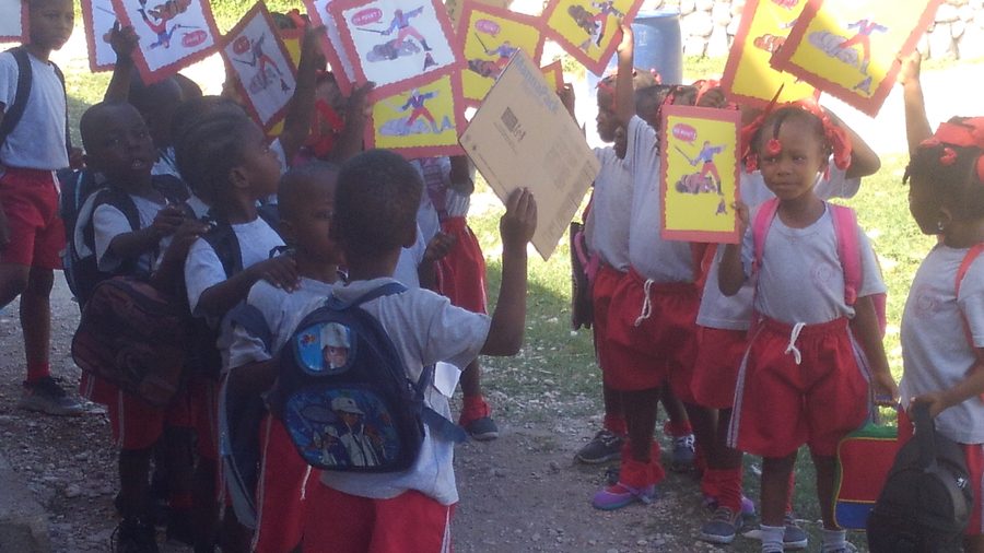 Students holding up illustrated reading books outdoors